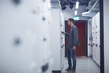 Male technician turning switch on in technical room - CUF32994