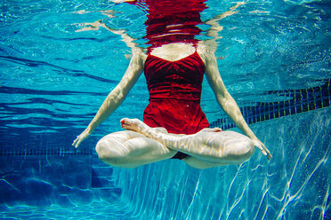 Reife Frau in rotem Kleid, Beine gekreuzt, Unterwasseransicht, Tiefschnitt - ISF10483