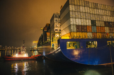 Tugboat manoeuvring container ship on river at night, Tacoma, Washington, USA - ISF10487