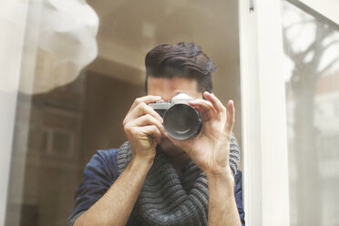 Porträt eines jungen Mannes beim Fotografieren mit einer Spiegelreflexkamera - CUF33046