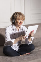 Frau benutzt digitales Tablet auf Sofa - CUF33063