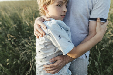 Junge, der seinen Vater auf einer Wiese umarmt - KMKF00365