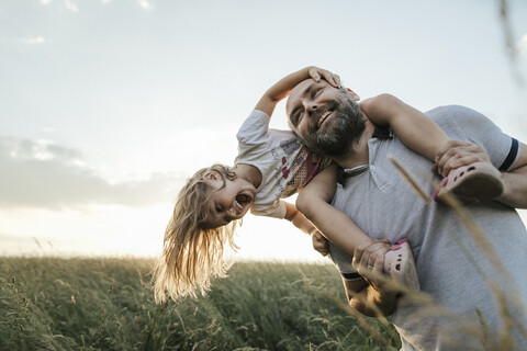 Älterer Mann spielt mit seiner kleinen Tochter in der Natur, lizenzfreies Stockfoto