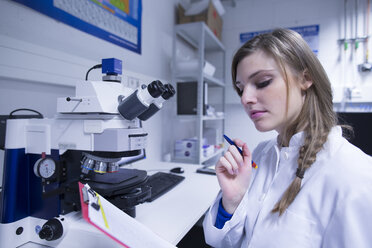 Wissenschaftlerin liest Notizen auf dem Klemmbrett im Labor - CUF33125