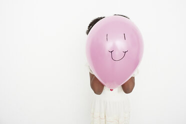 Girl blowing up balloon with smiley face - ISF10546