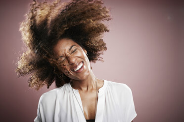 Portrait of young woman flicking hair, smiling - ISF10612