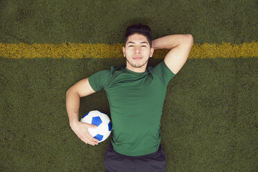 Overhead-Porträt eines jungen männlichen Fußballspielers auf dem Fußballfeld liegend - ISF10661