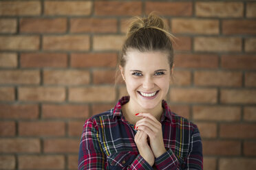 Portrait of laughing young woman in front of brick wall - AWF00053