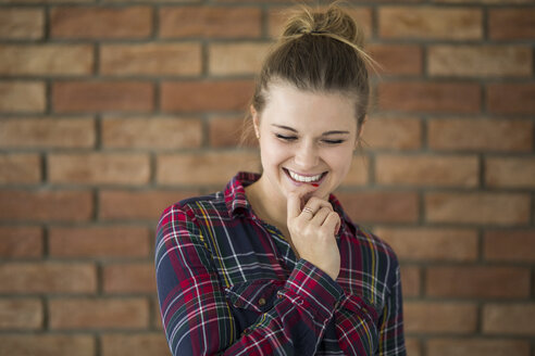 Portrait of hesitating young woman in front of brick wall - AWF00054