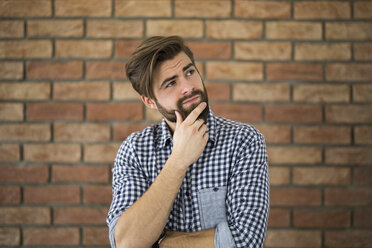 Portrait of pensive young man in front of brick wall - AWF00060