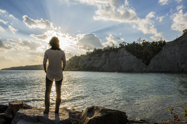 Mid adult woman on rocks, Scarborough Bluffs, Toronto, Canada - ISF10681