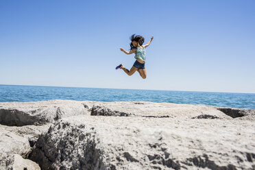 Young woman jumping over rocks, Scarborough Bluffs, Toronto, Ontario, Canada - ISF10689