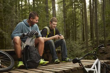 Zwei junge Männer mit Mountainbikes, im Wald, machen eine Pause - ISF10730