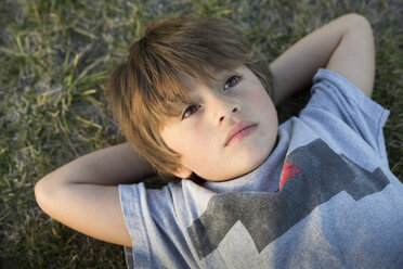 Porträt eines Jungen, der auf dem Rasen eines Parks liegt und nach oben blickt - ISF10765