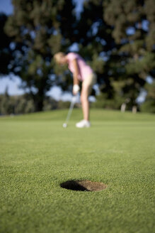 Young woman playing golf, focus on foreground - ISF10778