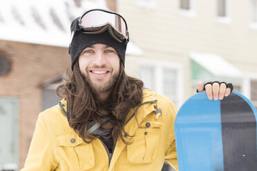 Porträt eines jungen Mannes mit Snowboard auf der Straße - ISF10790