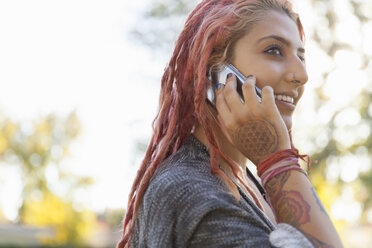 Young woman with pink dreadlocks chatting on smartphone in park - ISF10800