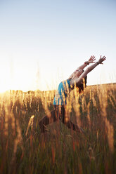 Mature woman practising yoga on field - ISF10808