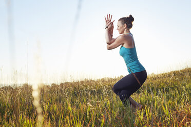 Mature woman practising yoga on field - ISF10809