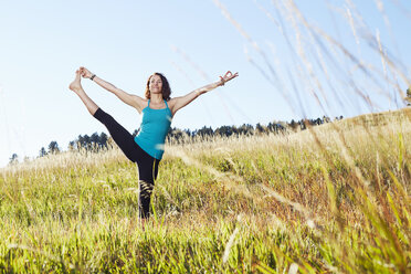 Mature woman practising yoga on field - ISF10814