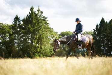 Girl horseback riding in field - ISF10873