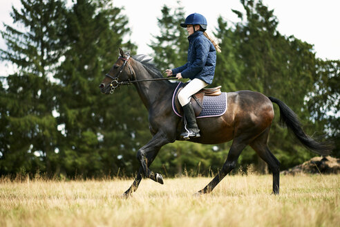 Mädchen reitet Pferd im Feld - ISF10894