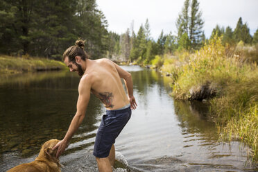 Junger Mann paddelt mit Hund im Fluss, Lake Tahoe, Nevada, USA - ISF10957