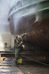 Werftarbeiter bei der Reinigung eines Bootes mit einem Hochdruckschlauch - ISF10960