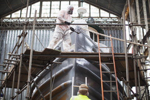 Arbeiter beim Lackieren eines Bootes in einer Werft, lizenzfreies Stockfoto