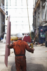 Rear view of worker using winch in shipyard workshop - ISF10984