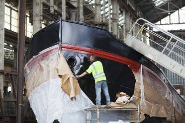 Arbeiter packen in der Werft ein Boot aus - ISF10985