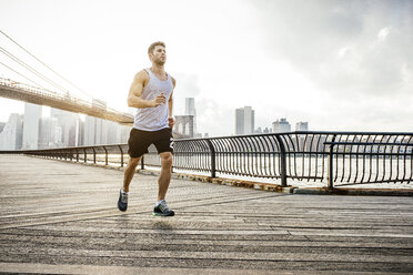 Young male runner running along riverside, Brooklyn, New York, USA - ISF11095