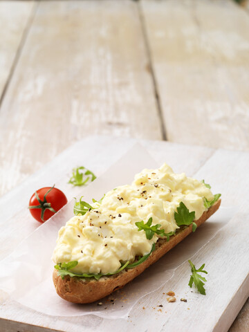 Eiermayonnaise mit gemahlenem Pfeffer auf knusprigem Baguette mit Salatblättern und Kirschtomaten, lizenzfreies Stockfoto