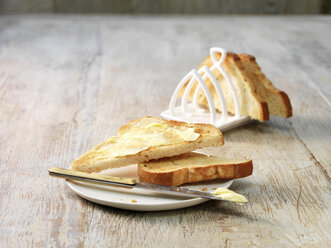 Schmelzende Butter auf geschnittenem Weißbrot auf Teller und Toastständer - ISF11118