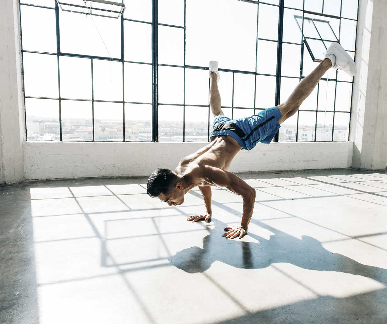 Young man in gym doing handstand, legs raised stock photo