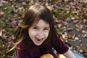 High angle portrait of young girl among autumn leaves looking at camera open mouthed smiling - ISF11225