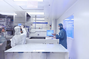 Arbeiter an Fertigungsmaschinen im Reinraum einer flexiblen Elektronikfabrik - ISF11247