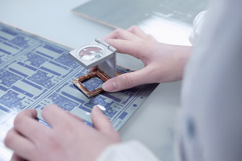 Hands of female worker inspecting flex circuit in flexible electronics factory stock photo