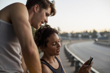 Jogger mit Mobiltelefon auf einer Brücke, Arroyo Seco Park, Pasadena, Kalifornien, USA - ISF11321