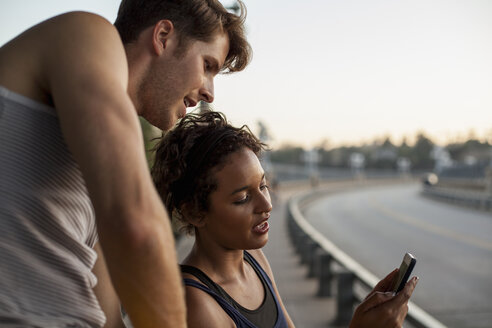 Jogger mit Mobiltelefon auf einer Brücke, Arroyo Seco Park, Pasadena, Kalifornien, USA - ISF11321