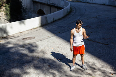 Jogger wählt Musik auf dem Smartphone aus, Arroyo Seco Park, Pasadena, Kalifornien, USA - ISF11334