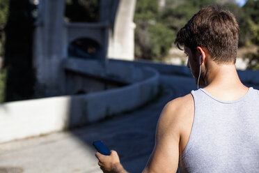 Jogger selecting music on smartphone, Arroyo Seco Park, Pasadena, California, USA - ISF11335