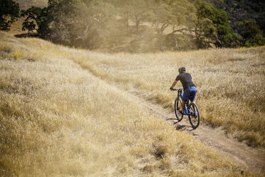 Erhöhte Rückansicht eines jungen Mannes beim Mountainbiking auf einer unbefestigten Strecke, Mount Diablo, Bay Area, Kalifornien, USA - ISF11344