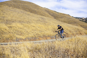 Junger männlicher Mountainbiker auf Landstraße, Mount Diablo, Bay Area, Kalifornien, USA - ISF11345