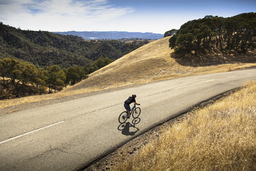 Blick von oben auf einen jungen Mann, der mit dem Mountainbike eine Landstraße hinunterfährt, Mount Diablo, Bay Area, Kalifornien, USA - ISF11346
