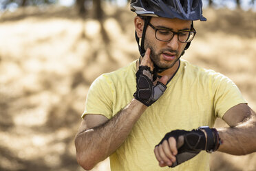 Junger männlicher Mountainbiker, der seine Smartwatch überprüft, Mount Diablo, Bay Area, Kalifornien, USA - ISF11348