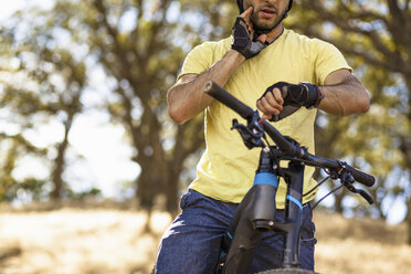 Beschnittene Ansicht eines jungen männlichen Mountainbikers, der seine Smartwatch überprüft, Mount Diablo, Bay Area, Kalifornien, USA - ISF11349