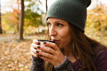 Junge Frau trinkt Kaffee im herbstlichen Wald - ISF11366