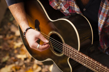 Ausgeschnittene Aufnahme eines jungen Mannes, der im Herbstwald Gitarre spielt - ISF11368