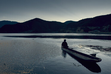 Silhouette einer Bergkette mit Mann im Boot, Luga-See, Yunnan, China - ISF11413